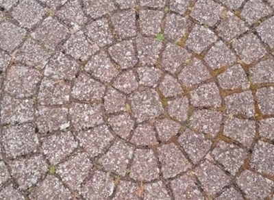 Belægningssten i cirkelmønster før fliserens med alger