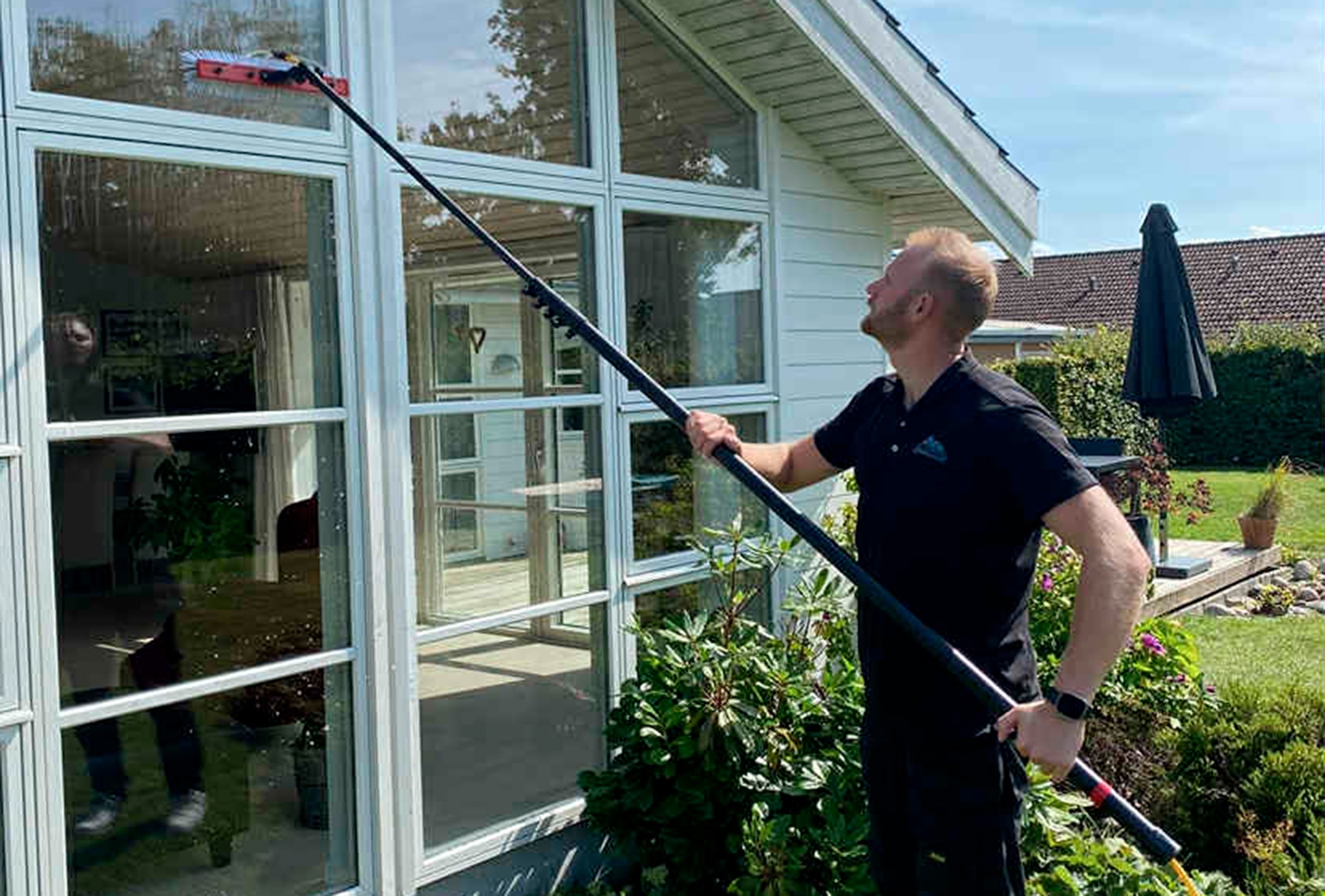 Faglært vinduespudser fra Westergaards Multirens udfører vinduespudsning på hus i Kalundborg